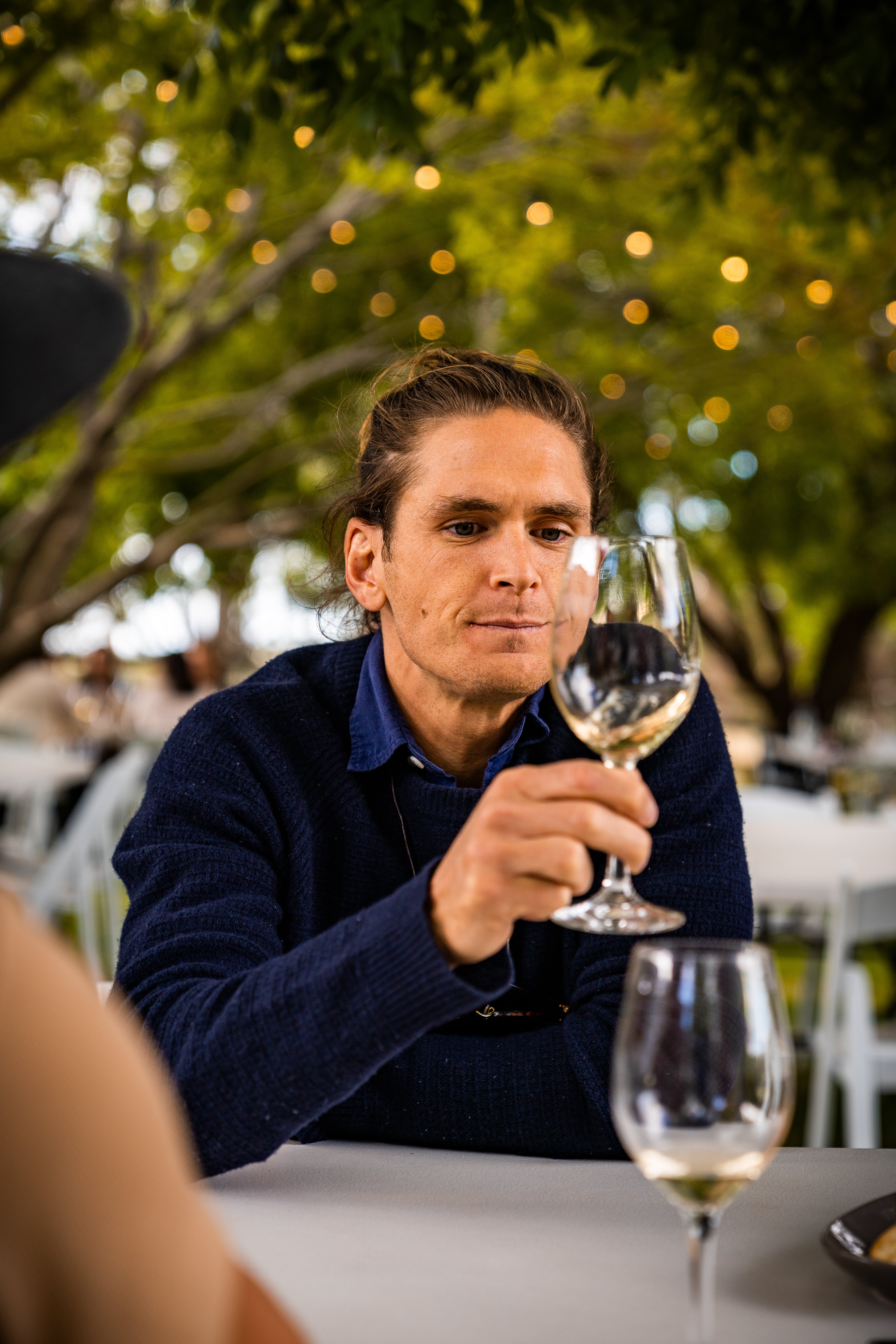 Man holding a glass of white wine outdoors with blurred background at Stockman's Ridge Wines