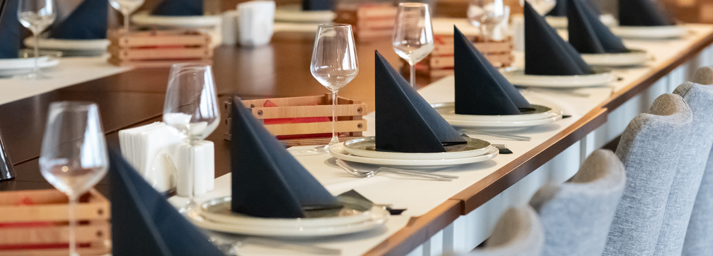 Dining table set with black napkins, glasses, and plates in an event space