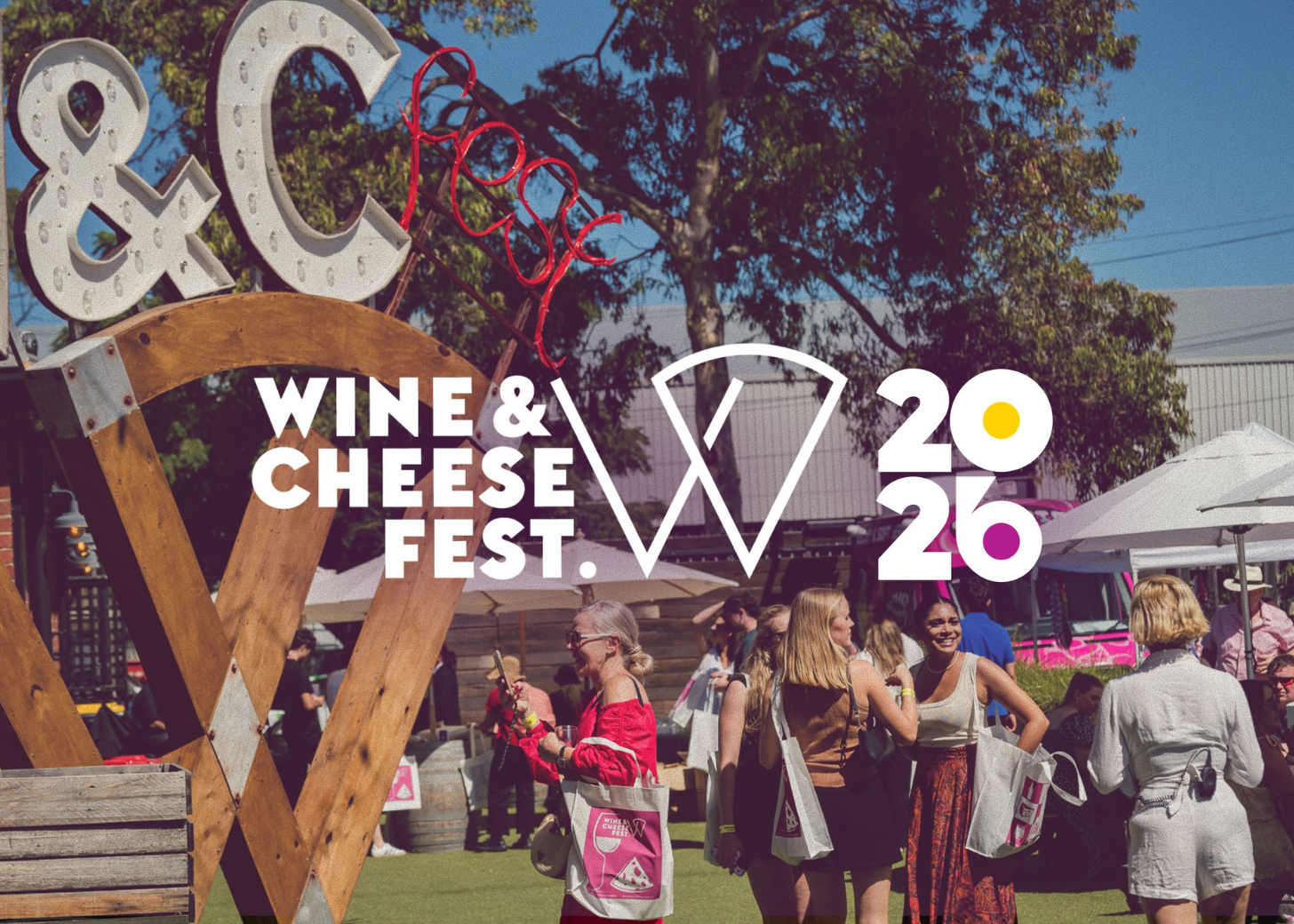 Wine & Cheese Fest 2026 event with attendees and a large wooden sign.