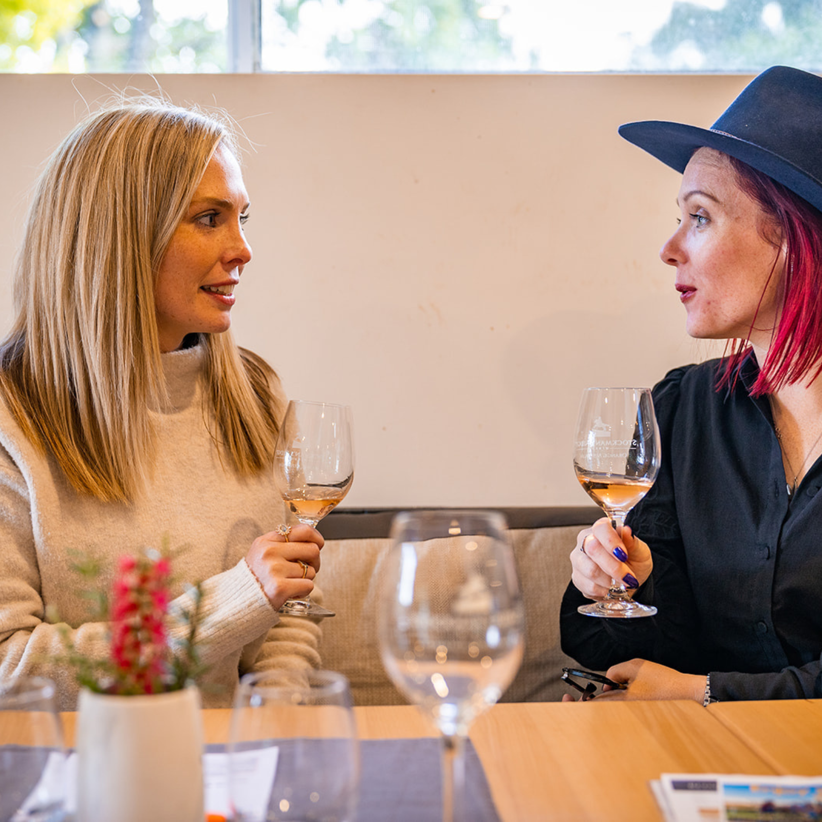 Two women sitting at a table with wine glasses, engaged in conversation at Stockman's Ridge ines