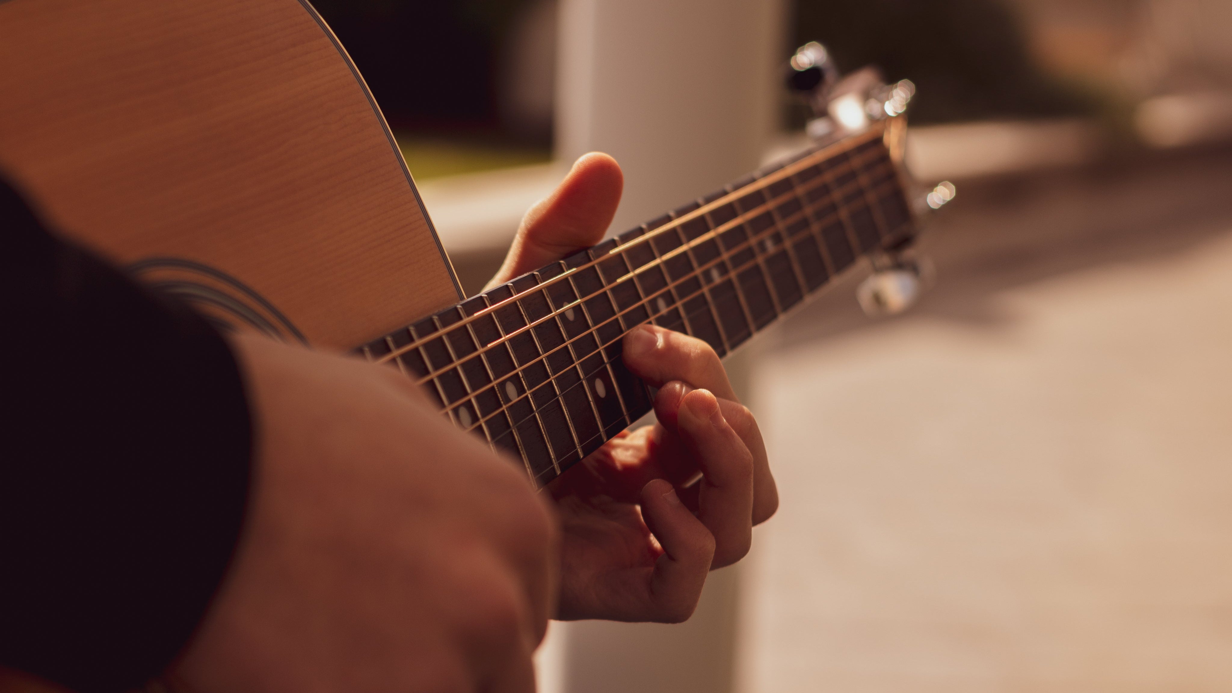 Close-up of hands playing an acoustic guitar with a blurred background