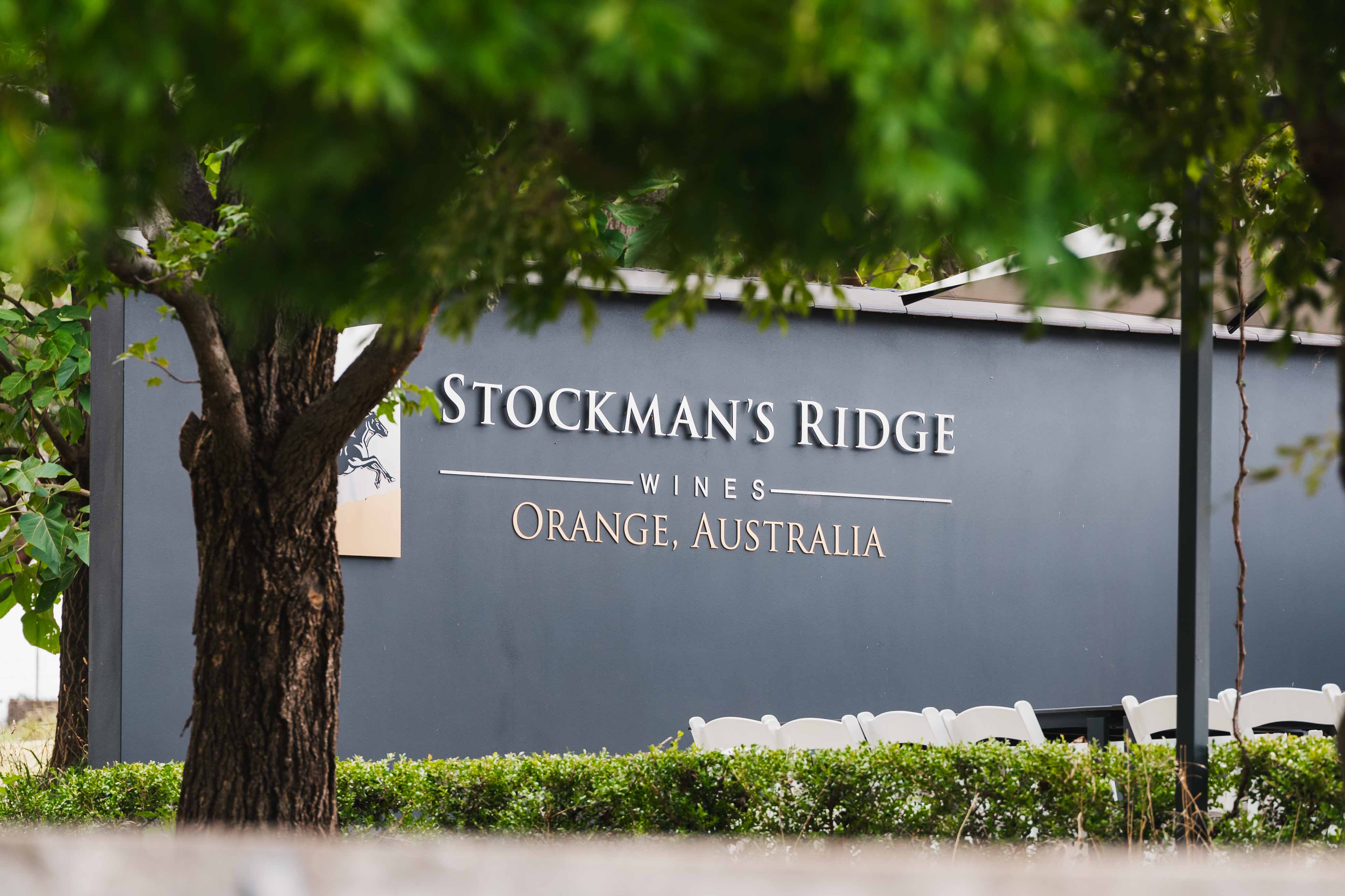 Stockman's Ridge Wines sign with trees and seating area in the background