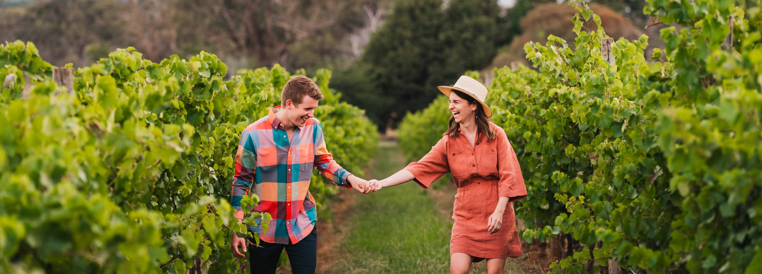 Two people walking through a vineyard at Stockman's Ridge Wines holding hands.