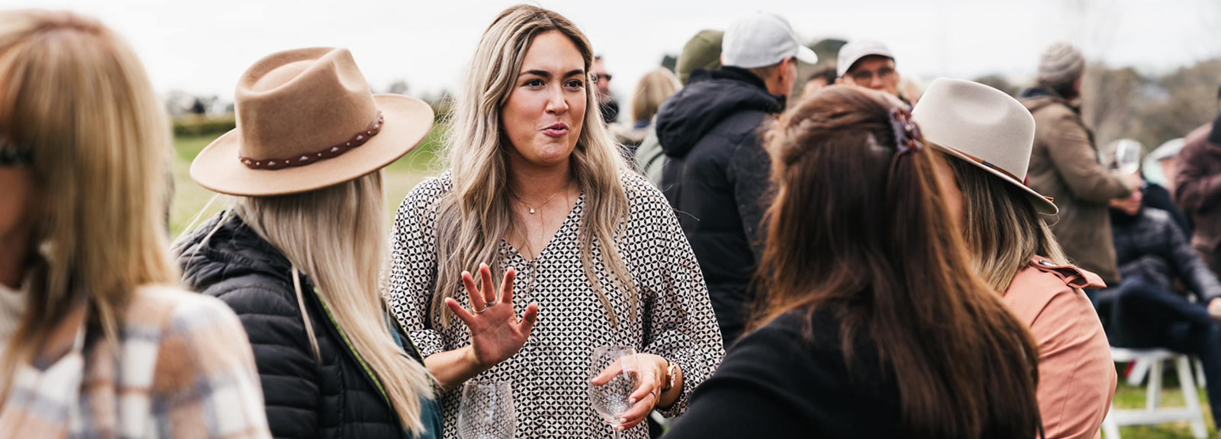 Woman in a patterned dress talking to others at an outdoor event at Stockman's Ridge Wines