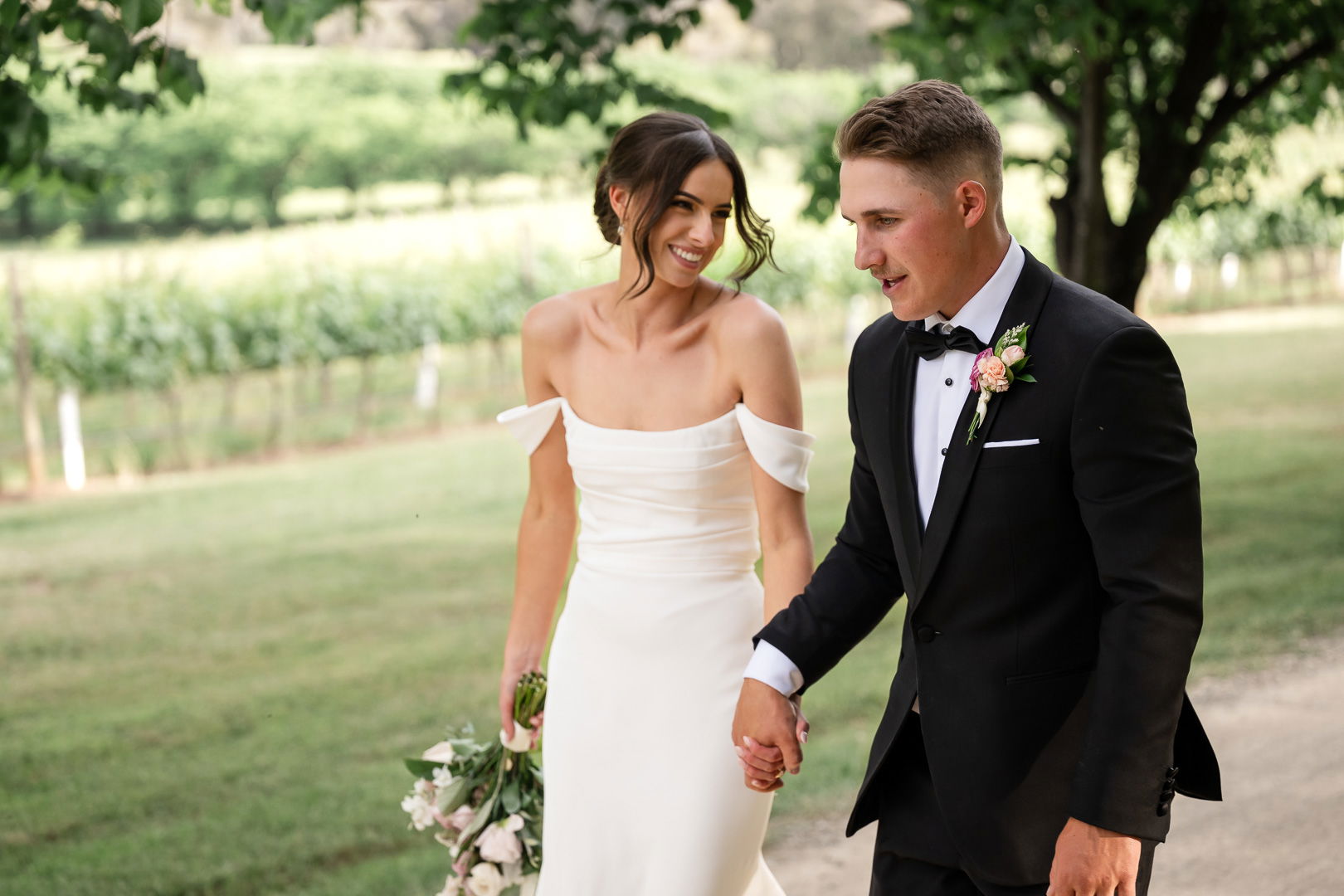 Couple in wedding attire standing outdoors with a vineyard background at Stockman's Ridge Wines