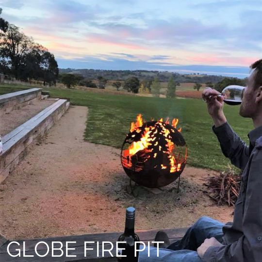 A man drinking wine around a globe shaped firepit at Stockman's Ridge Wines